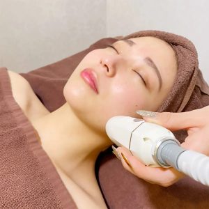 Beauty Salon Lilyで女性がフェイシャルエステを受けている様子。施術者が機器を使い顔に当てている