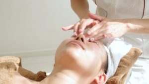 Beauty Salon Lilyでフェイシャルエステを受ける女性、エステティシャンが顔をマッサージ