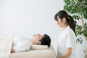 Beauty Salon Lilyで男性がエステベッドに横たわり、女性スタッフが笑顔で見守る施術風景