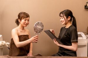 Beauty Salon Lilyでカウンセリングを受ける女性客とエステティシャン。女性客は鏡を見ている