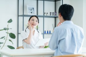 Beauty Salon Lilyで女性スタッフが男性客にフェイシャルエステについて説明する様子