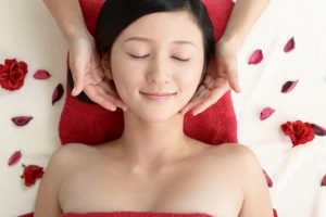 Beauty Salon Lilyのフェイシャルエステで顔をマッサージされ目を閉じ微笑む女性とバラの花びら